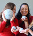 three female models holding different size blue calcite spheres
