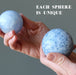 holding two different sizes of blue calcite spheres
