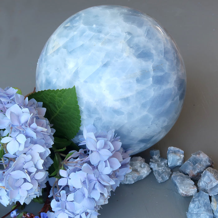 extra large blue clacite sphee with raw blue calcite stones and blue flowers