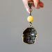 holding Yellow Calcite bead and display the back of brass Buddha Pendant 