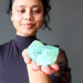 woman holding a pile of waxy green calcite raw stones