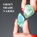 hands holding waxy green calcite raw stones