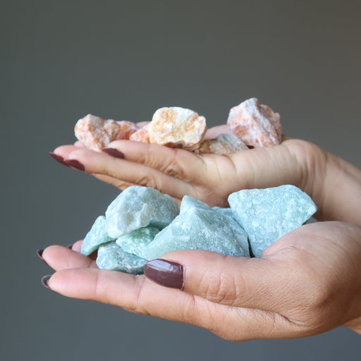 hands holding rough red and green calcite