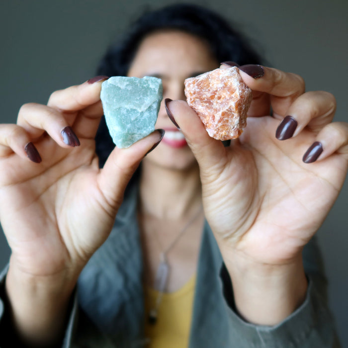 sheila of satin crystals holding a red and a green calcite stone