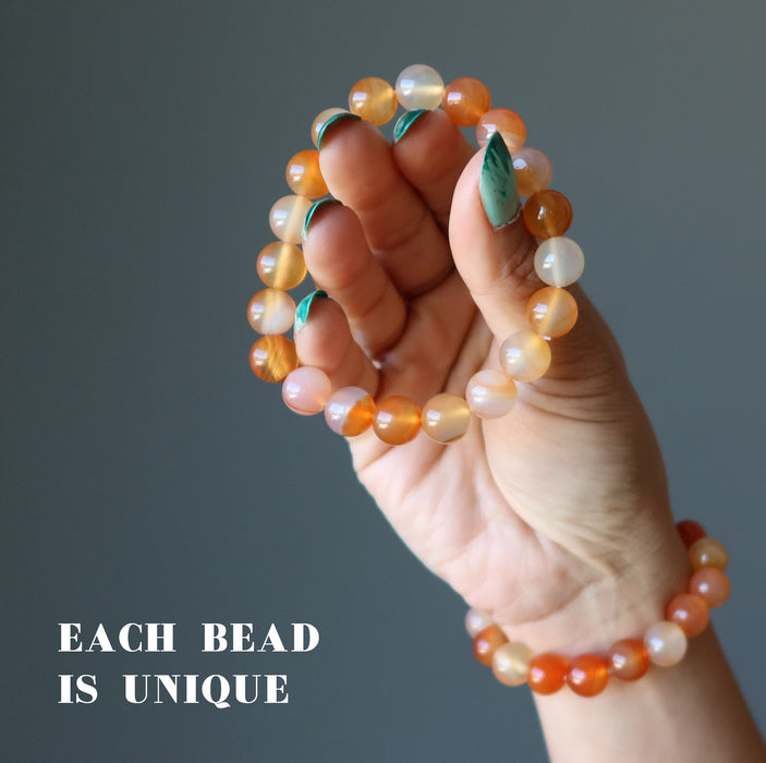 hand holding two carnelian braclets showing each bead is unique