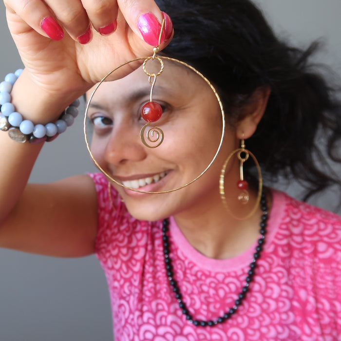 female holding carnelian hoop earrings