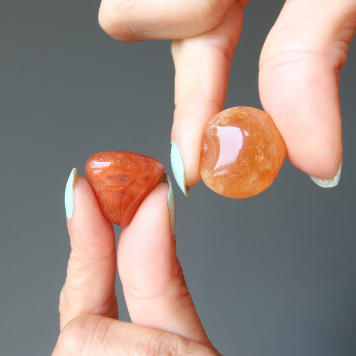 hand holding a carnelian tumbled stones