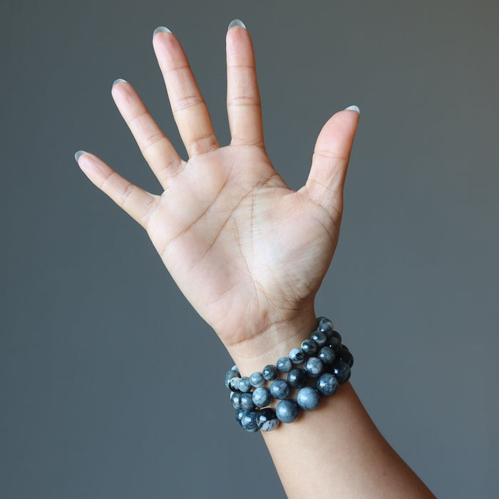hand wearing three sizes of cats eye quartz bracelets