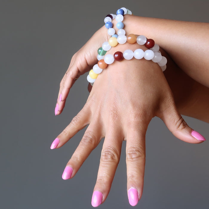 two hands wearing 4 snow white quartz chakra bracelets