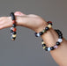 hand holding and wearing 3 rainbow obsidian and natural chakra stone stretch bracelets