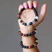 hand holding 1 and wearing 2 rainbow obsidian and natural chakra stone stretch bracelets