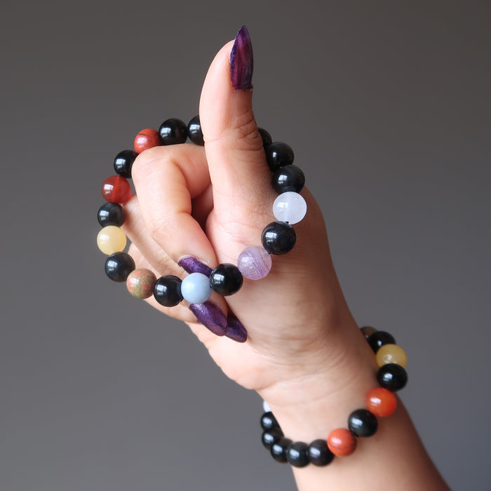 hand holding 1 and wearing 1 rainbow obsidian and natural chakra stone stretch bracelets