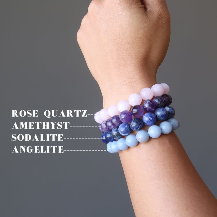 hand wearing upper chakra bracelet set including purple amethyst, blue sodalite, light blue angelite, pink rose quartz