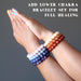 hands wearing upper and lower chakra bracelet sets