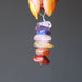 hand holding a stacked gemstone chakra pendant 