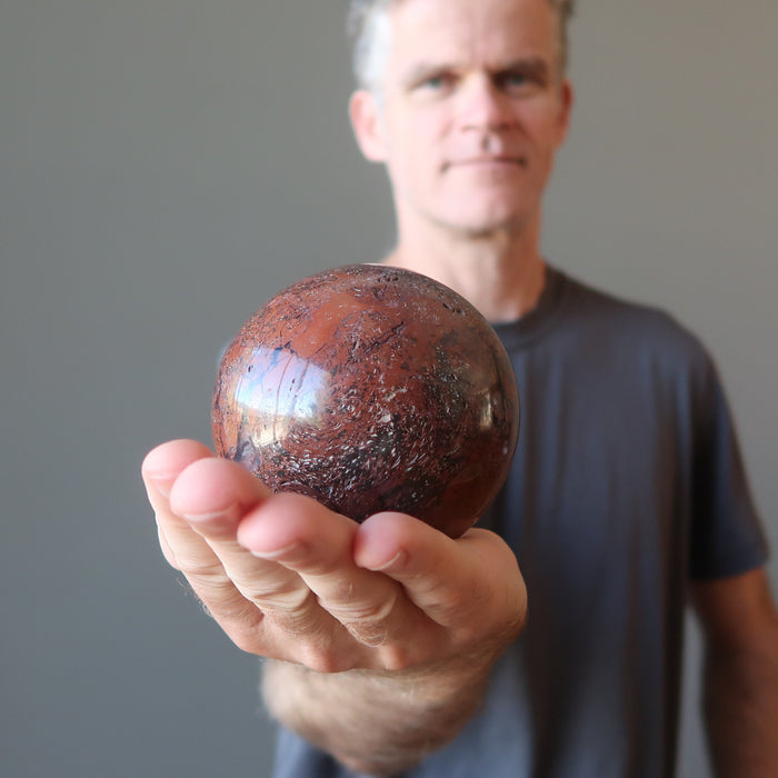 male model holding red chalcedony sphere in his hand