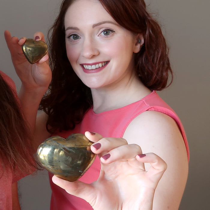 two female models holding gold Chalcopyrite Heart 