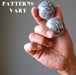 hand holding two chrysanthemum stone spheres to show varying patterns
