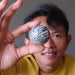 tim of satin crystals holding up a chrysanthemum stone ball in front of his eye