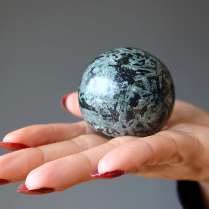 Green Tourmaline Sphere displaying on the palm