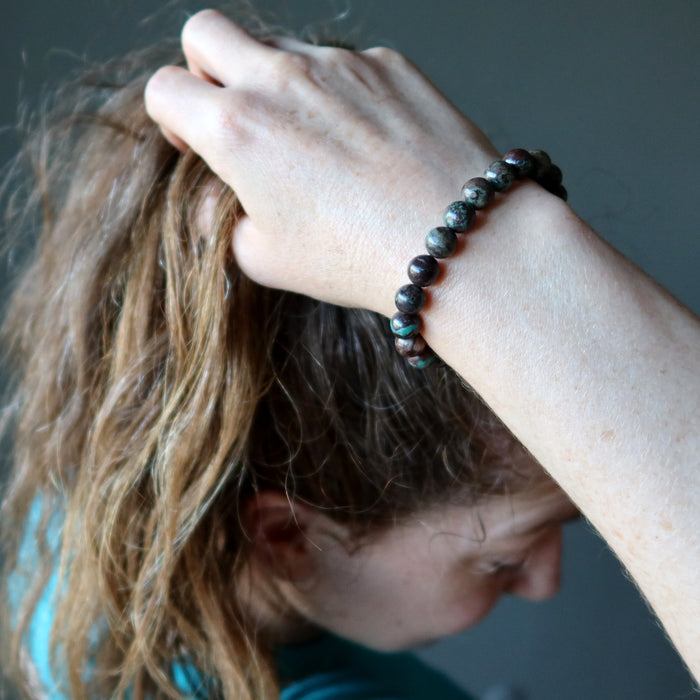 female model with hand at top of her head wearing chrysocolla cuprite bracelet