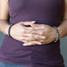 female hands clasped at stomach wearing chrysocolla cuprite bracelets in each wrist