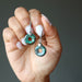 hand holding sheila of Satin Crystals wearing blue Chrysocolla donut Earrings 
