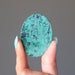 hand holding blue-green and black chrysocolla oval cabochon showing the flat back