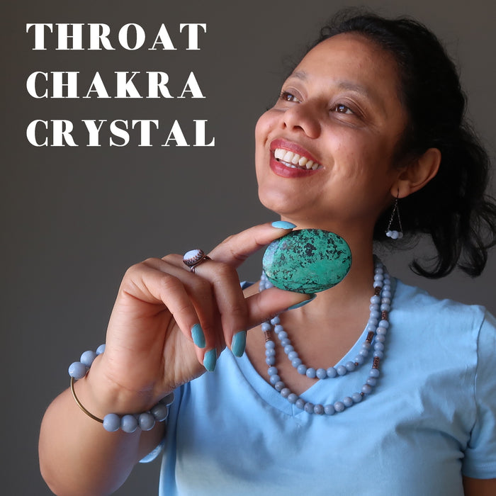 sheila of satin crystals holding blue-green and black chrysocolla oval cabochon at her throat chakra