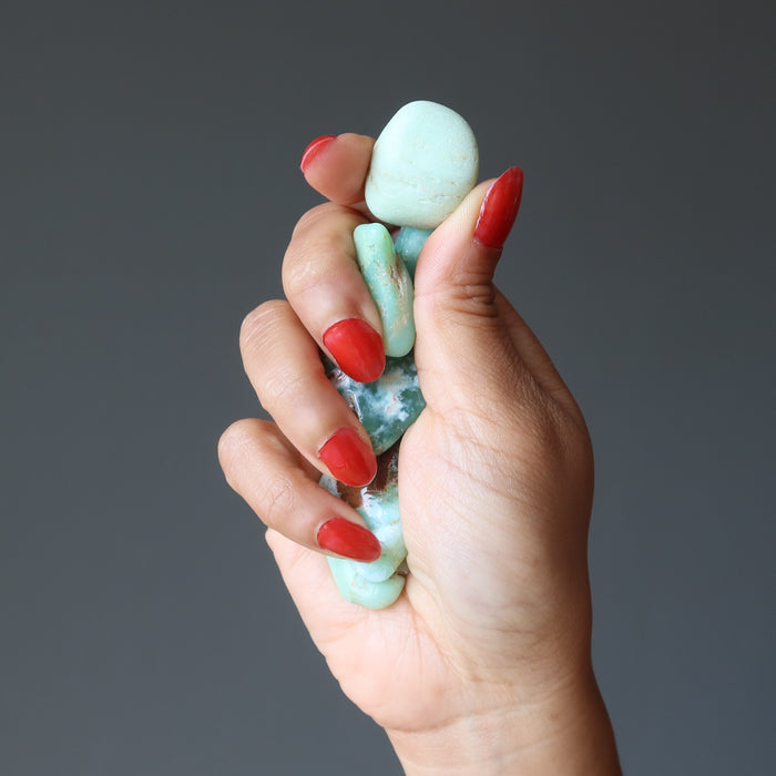 hand holding two chrysoprase tumbled stones