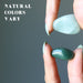 hand holding two aventurine tumbled stones with varying shades of green