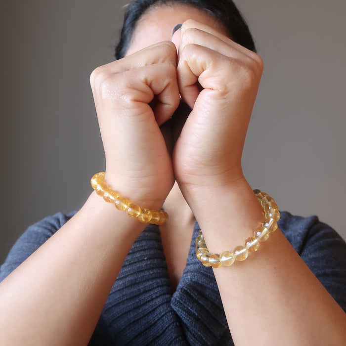 female with hands together modeling yellow citrine beaded stretch bracelets on each wrist