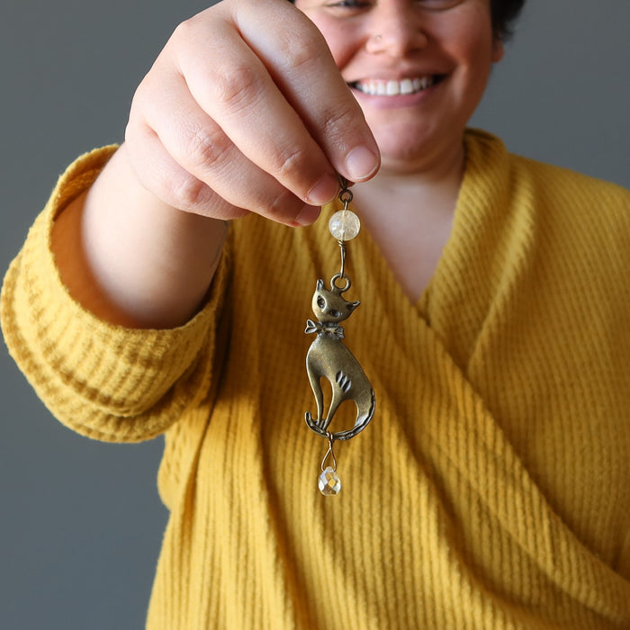 female model holding brass feline hangs with faceted yellow Citrine drops from a polished Citrine orb on a long pendant