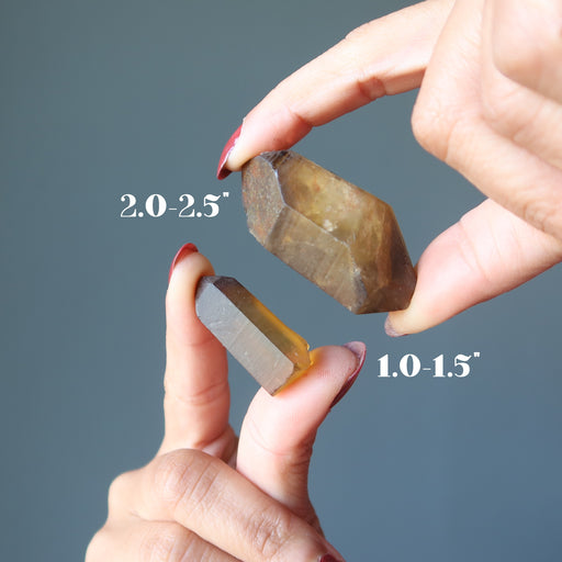 hands holding raw yellow citrine points to show size difference