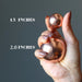 hand holding two copper spheres in different sizes
