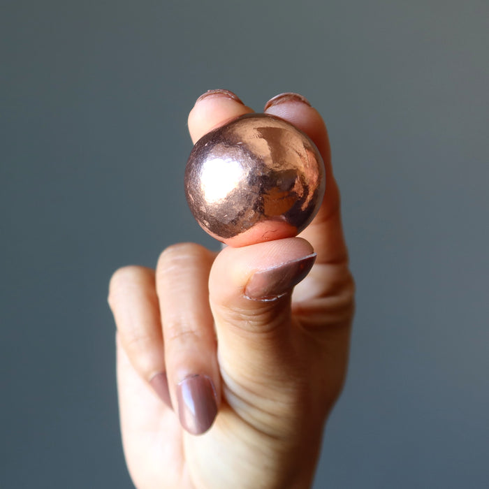 hand holding a small copper sphere