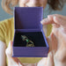 model holding Swinging Bird green Diopside Pendant in purple gift box