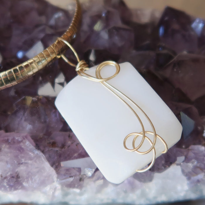 wavy rectangle white Dolomite stone wrapped in gold plated wire pendant hangs on Gold plated choker on amethyst cluster