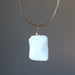 back of wavy rectangle white Dolomite stone wrapped in gold plated wire pendant hangs on Gold plated choker