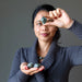 woman holding tumbled emerald stones at third eye