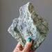 hand holding rough green epidote standing mineral stone