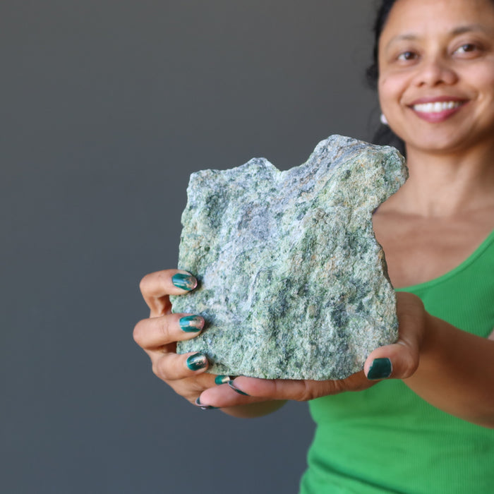 sheila of satin crystals holding rough green epidote standing mineral stone
