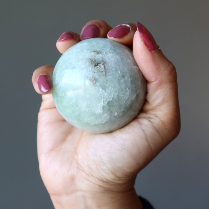 holding Creamy Green Fluorite Spheres on the palm