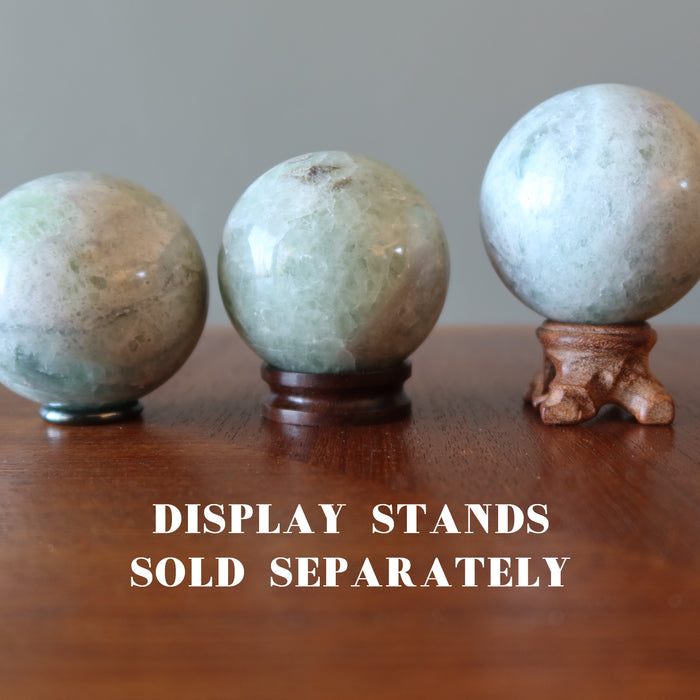 holding 3 Creamy Green Fluorite Spheres on stands which sold separately