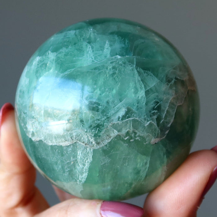 holding green Fluorite Sphere 