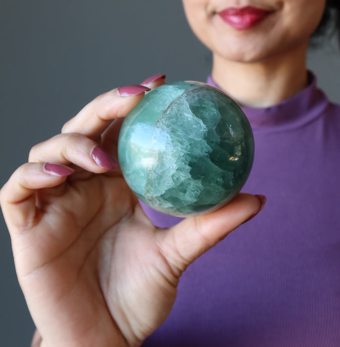 holding green Fluorite Sphere 