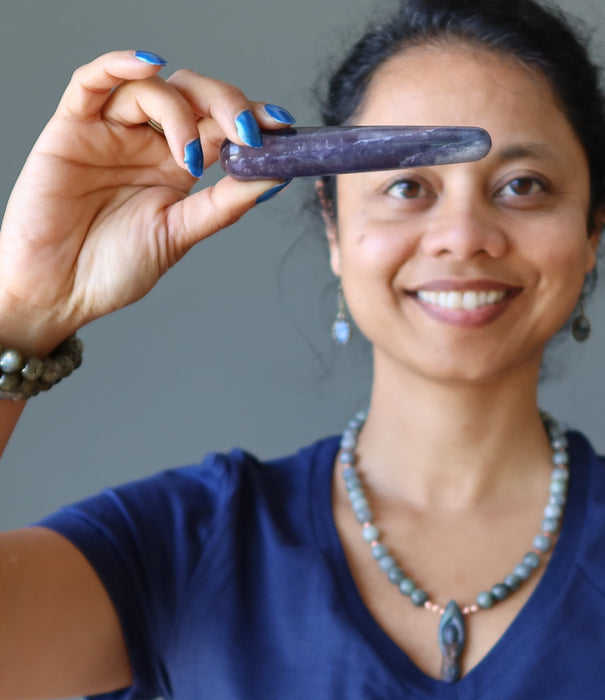 sheila of satin crystals holding a purple fluorite to her third eye chakra