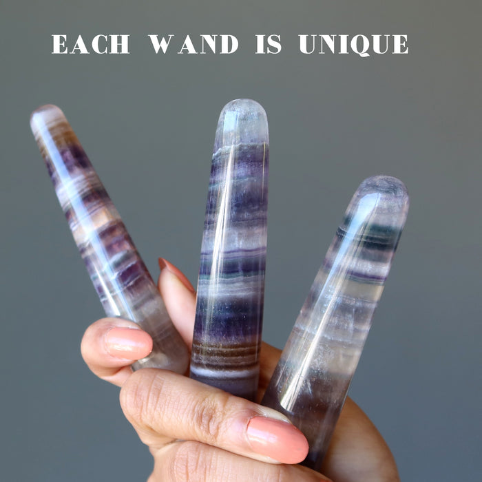 hand holding 3 rainbow fluorite tapered massage wands