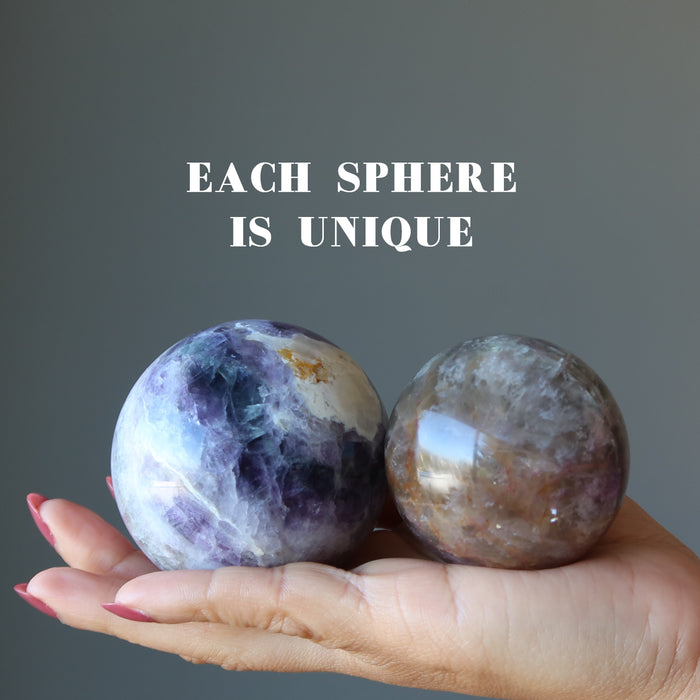 holding two purple rainbow Fluorite Spheres on the palm