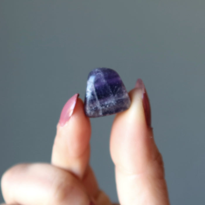 fingers holding a tumbled fluorite 